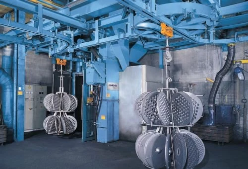Hanger blasting chambers with suspended perforated metal components on rotating hooks